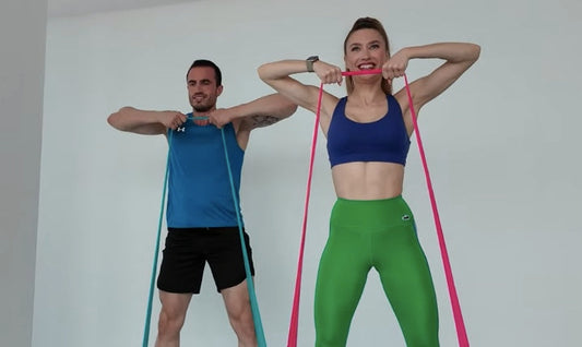Man and woman doing resistance band squat upright row for full-body strength – Bir erkek ve bir kadın tam vücut kuvveti için direnç bandı squat upright row yapıyor.